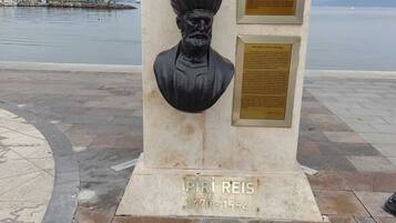 A statue of a historical figure with plaques and a name plaque at the base.