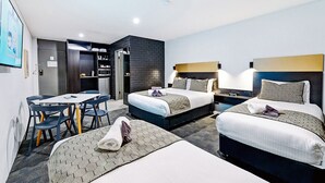 A hotel room with two beds, a dining table, and a kitchenette.