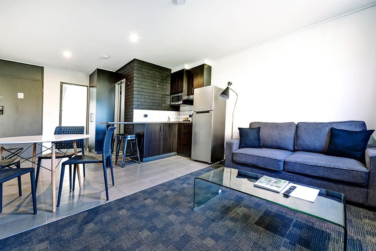 A modern living room with a sofa, coffee table, and dining area.