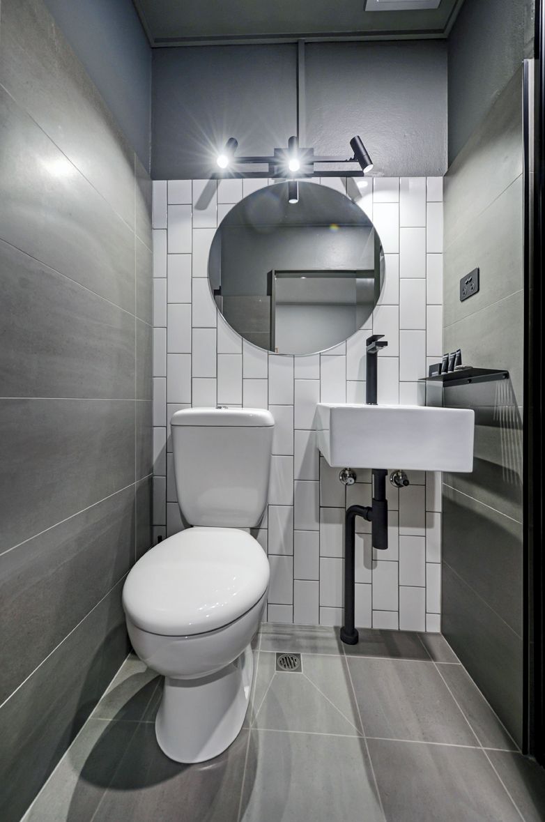 Un baño moderno con inodoro, lavamanos y espejo.