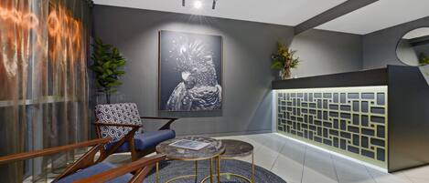 A modern lobby with a blue sofa, a round table, and a large abstract painting.