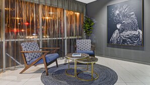 A modern room with two patterned chairs, a small round table, and a large abstract painting on the wall.