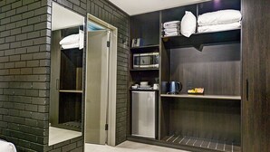 A modern hotel room with a dark wood wardrobe, a built-in microwave, and a small refrigerator.