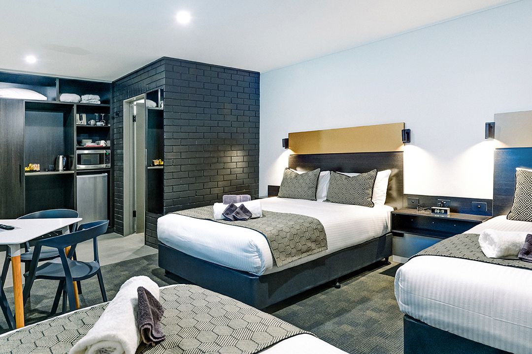 A hotel room with a bed, a desk, and a chair.