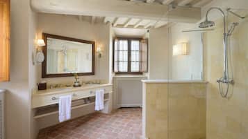 Un baño con un espejo grande, dos lavamanos, una ducha y un ventanal con persianas.