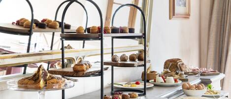 A buffet setup with multiple serving stations, including a variety of pastries, breads, and a bowl of eggs.