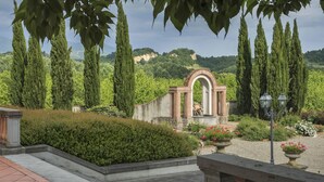 Un jardin aménagé avec une fontaine, de grands cyprès et une arche en briques.