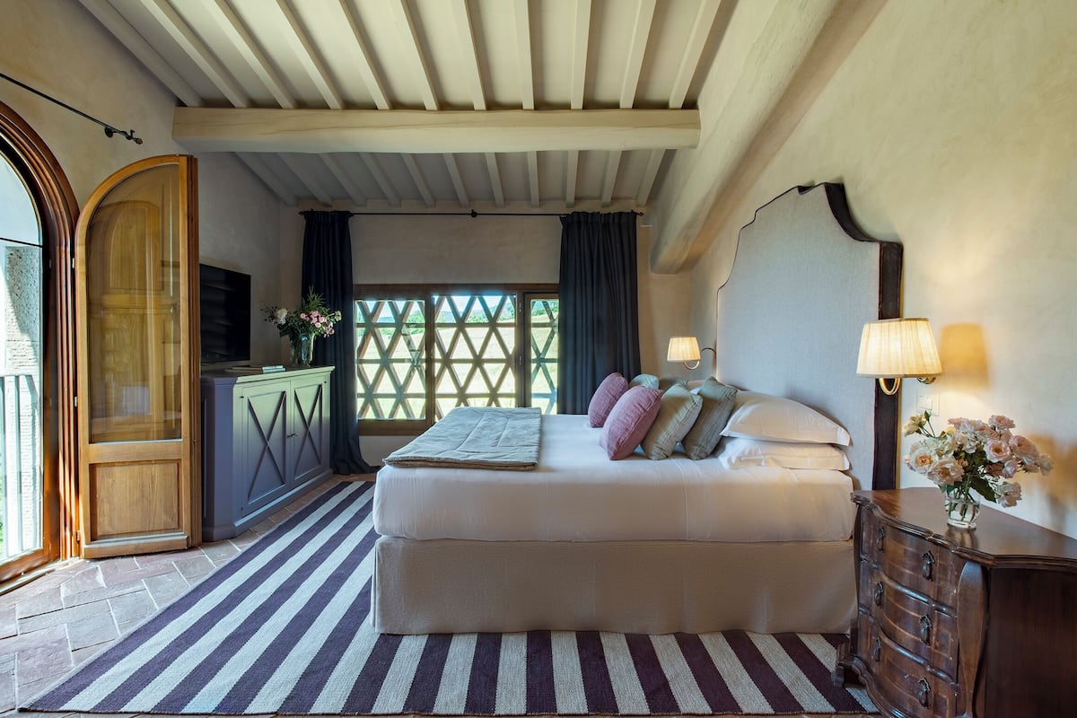 Een slaapkamer met een bed, een dressoir en een groot raam.