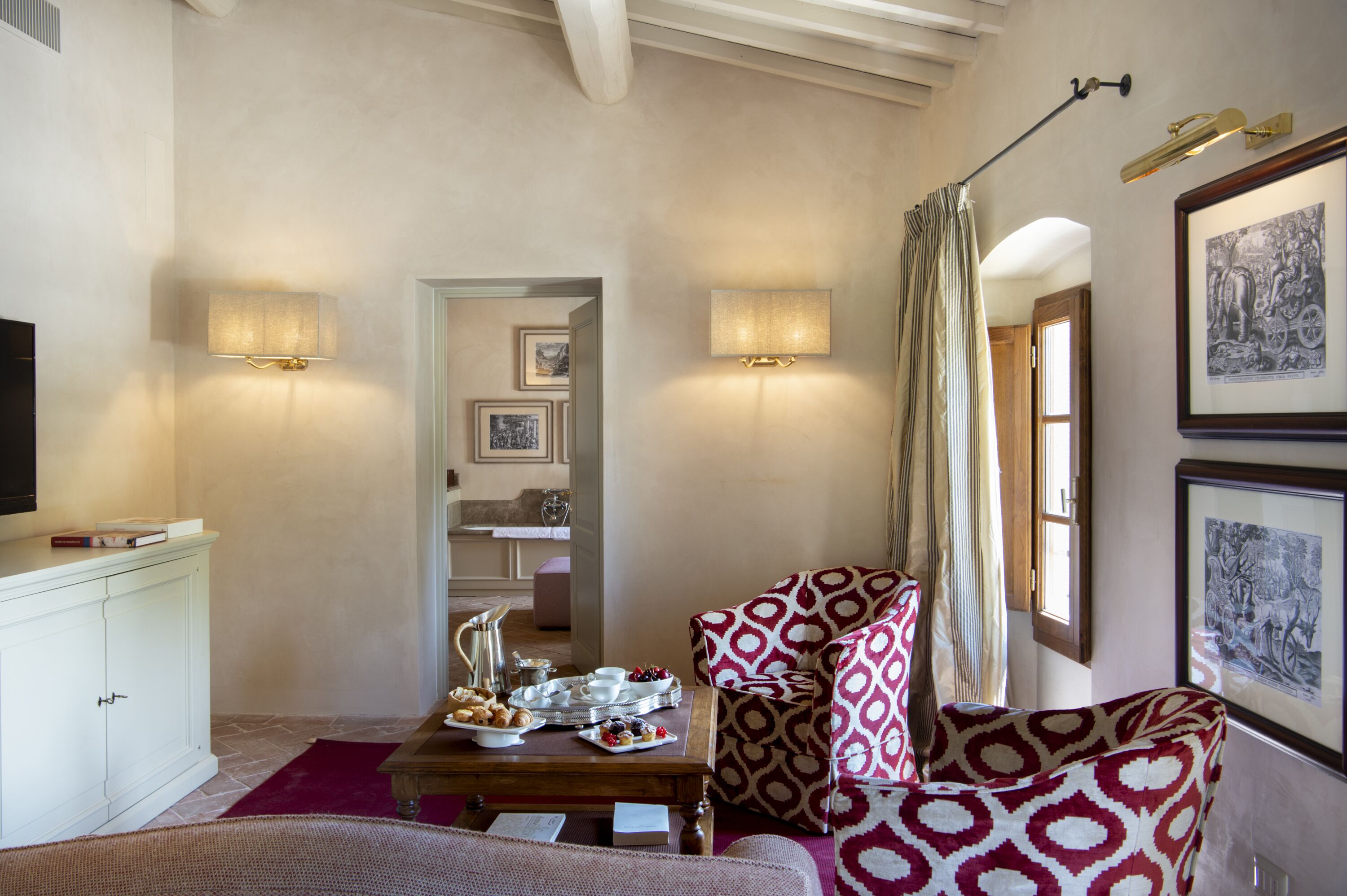 A cozy living room with a fireplace, a coffee table with snacks, a television, and two wall-mounted lamps.