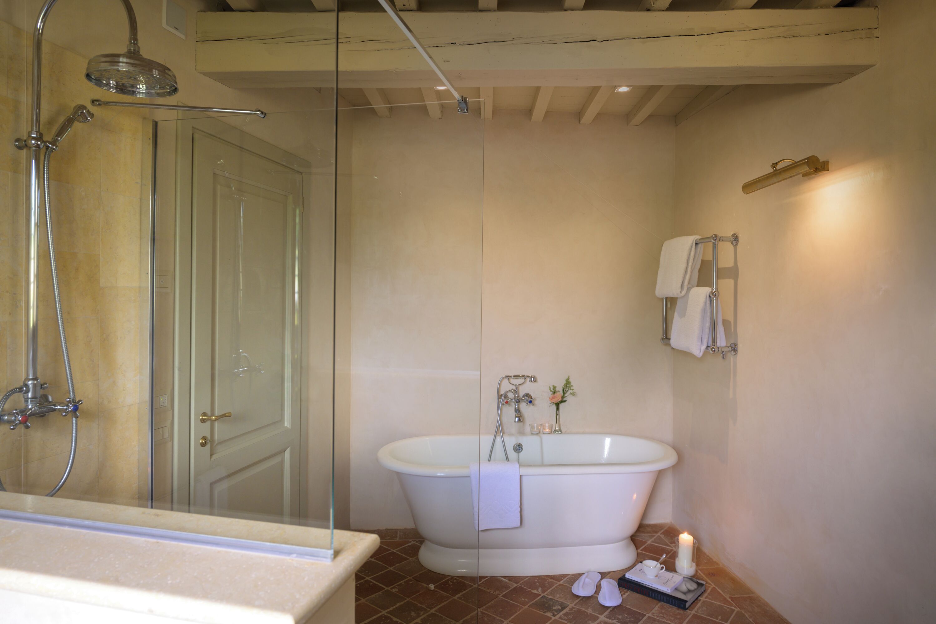 A bathroom with a glass-enclosed shower, a freestanding bathtub, and a white door.