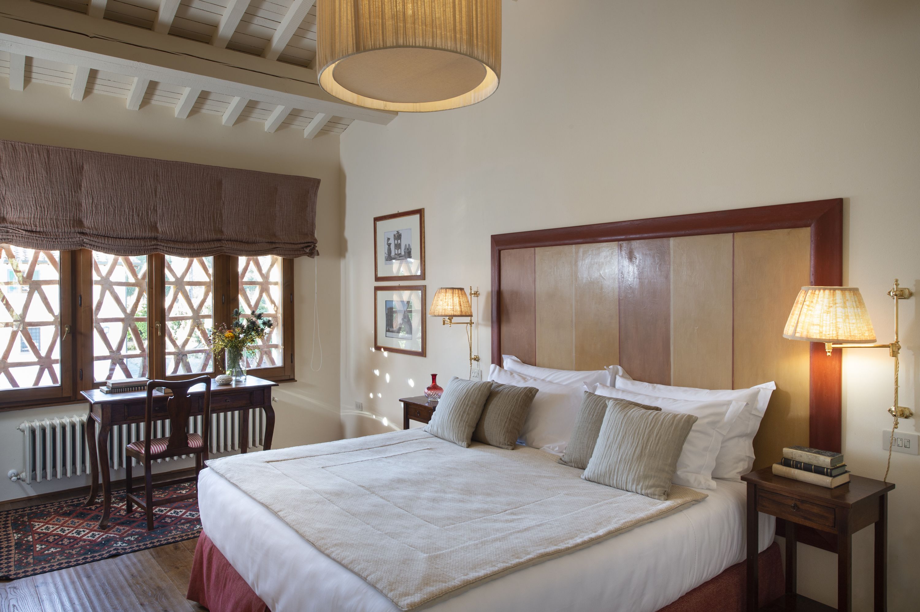 A neatly arranged bedroom with a large bed, a wooden headboard, a desk, and a chair.