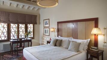 A neatly arranged bedroom with a large bed, a wooden headboard, a desk, and a chair.