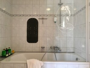 A modern bathroom with a bathtub, a shower, and a black mat on the wall. - Apartment Casa del Monte (Sinsheim)