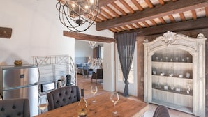 Un coin repas avec une table en bois, des chaises, un lustre et un meuble à vin.
