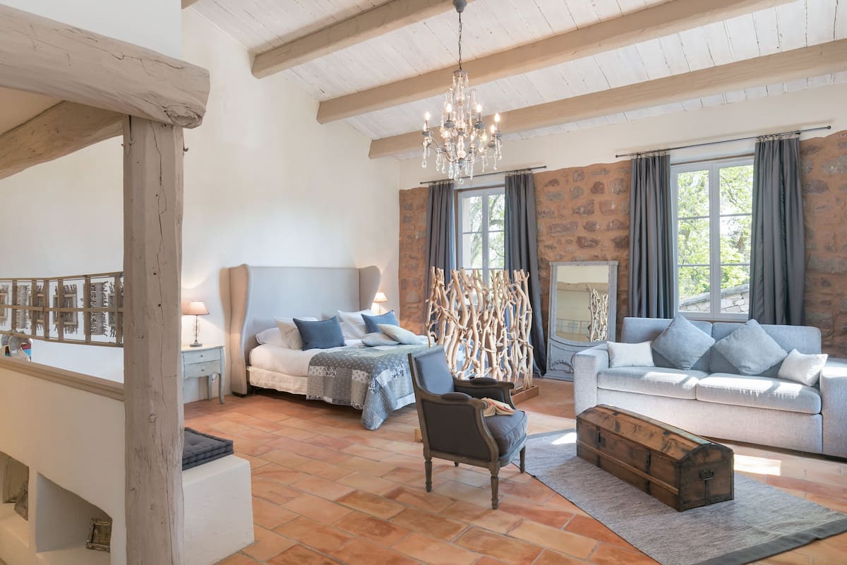Un salon spacieux comprenant un lit, un canapé et une commode en bois.