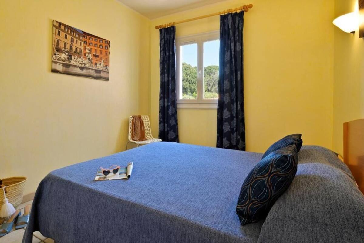 Une chambre à coucher avec un lit, une fenêtre avec des rideaux, un tableau au mur et une lampe.