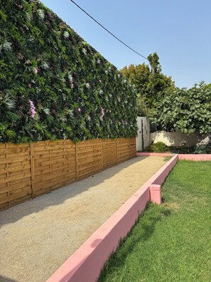 A garden with a wooden fence, a gravel path, and a green lawn. - Résidence Villa Romana et SPA (Propriano)