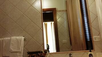 Une salle de bain avec un mur carrelé, un lavabo, un miroir et une serviette accrochée au mur.