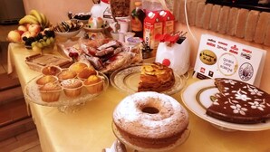 Uma mesa com diversos itens de comida, incluindo muffins, um bolo e uma sobremesa de chocolate.