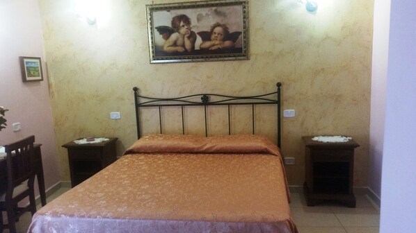 A bedroom with a bed, two bedside tables, a chair, and a painting on the wall. - Camere Primavera B&B (Fondi)