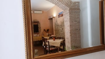 Un comedor con pared de ladrillo, una mesa con sillas y un espejo que refleja el ambiente.