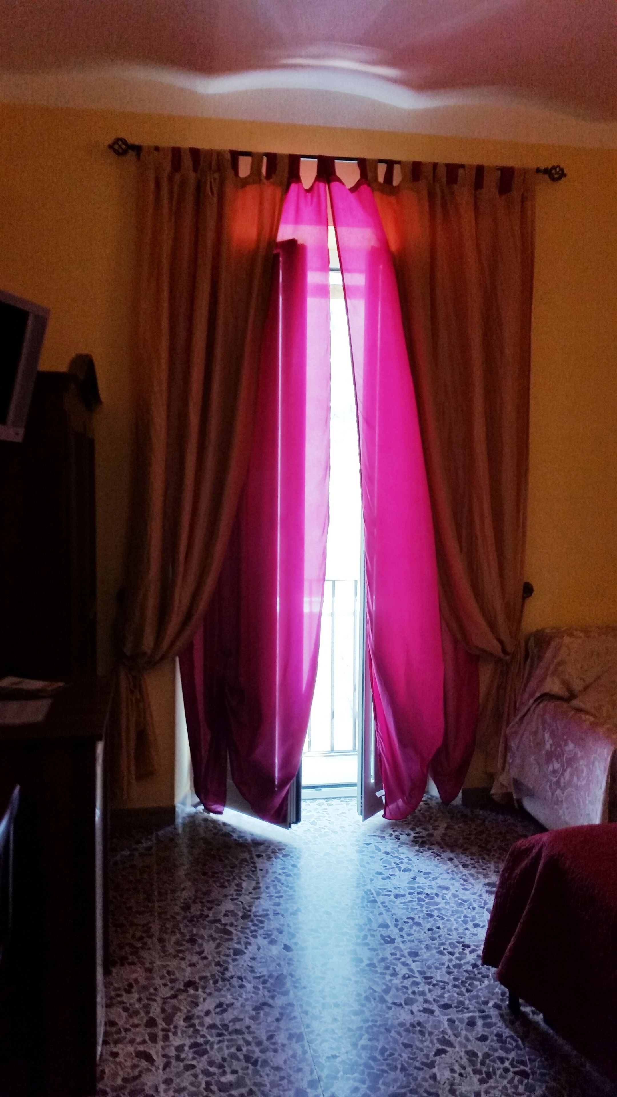Una habitación con piso estampado, una cama, un escritorio y una ventana con cortinas.