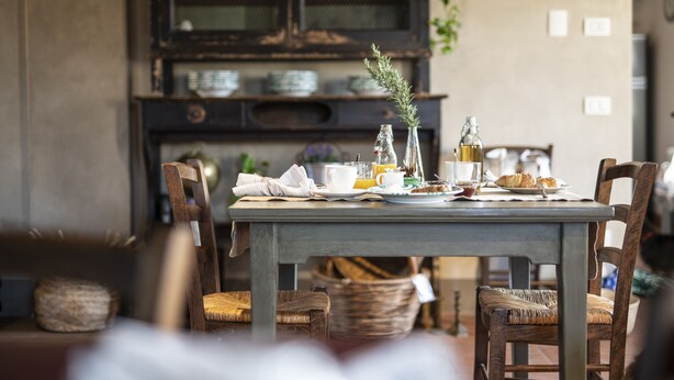 A dining table set with breakfast items, surrounded by wooden chairs and a wicker basket. - Agriturismo Borgoluce (Susegana)