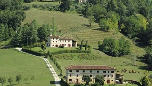 A large, two-story building with a tiled roof, surrounded by lush green fields and trees, with mountains in the background. - Agriturismo Borgoluce (Susegana)