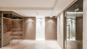 A modern hotel lobby with a glass partition, wooden benches, and a tiled floor. - Alpin Life Hotel Gebhard (Fiss)