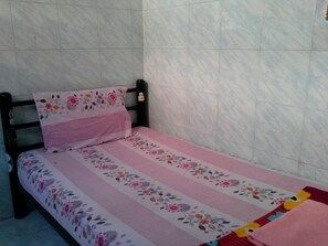 A small bed with a floral bedspread and a matching pillow, set against a tiled wall. - New Central Guesthouse (Bangkok)