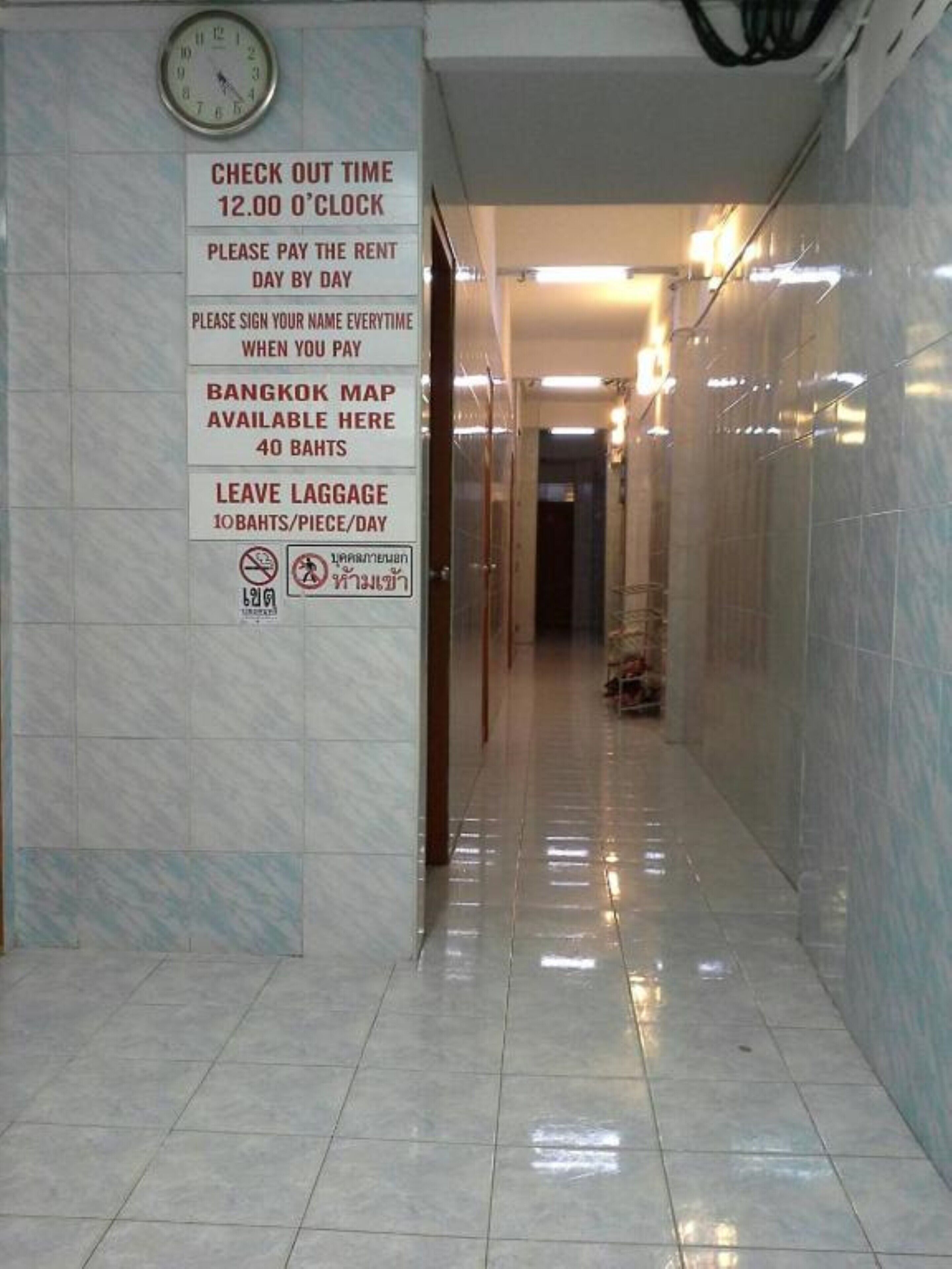 A hotel corridor with a clock, a sign detailing check-out time, and instructions for payment and luggage.