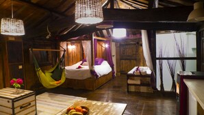 A rustic wooden room with a bed, a hammock, and a dining area with fruits. - El Bosque de las Viñas (Boal)