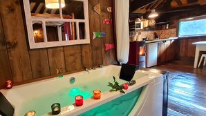 A wooden interior with a bathtub, candles, and a kitchen area. - El Bosque de las Viñas (Boal)