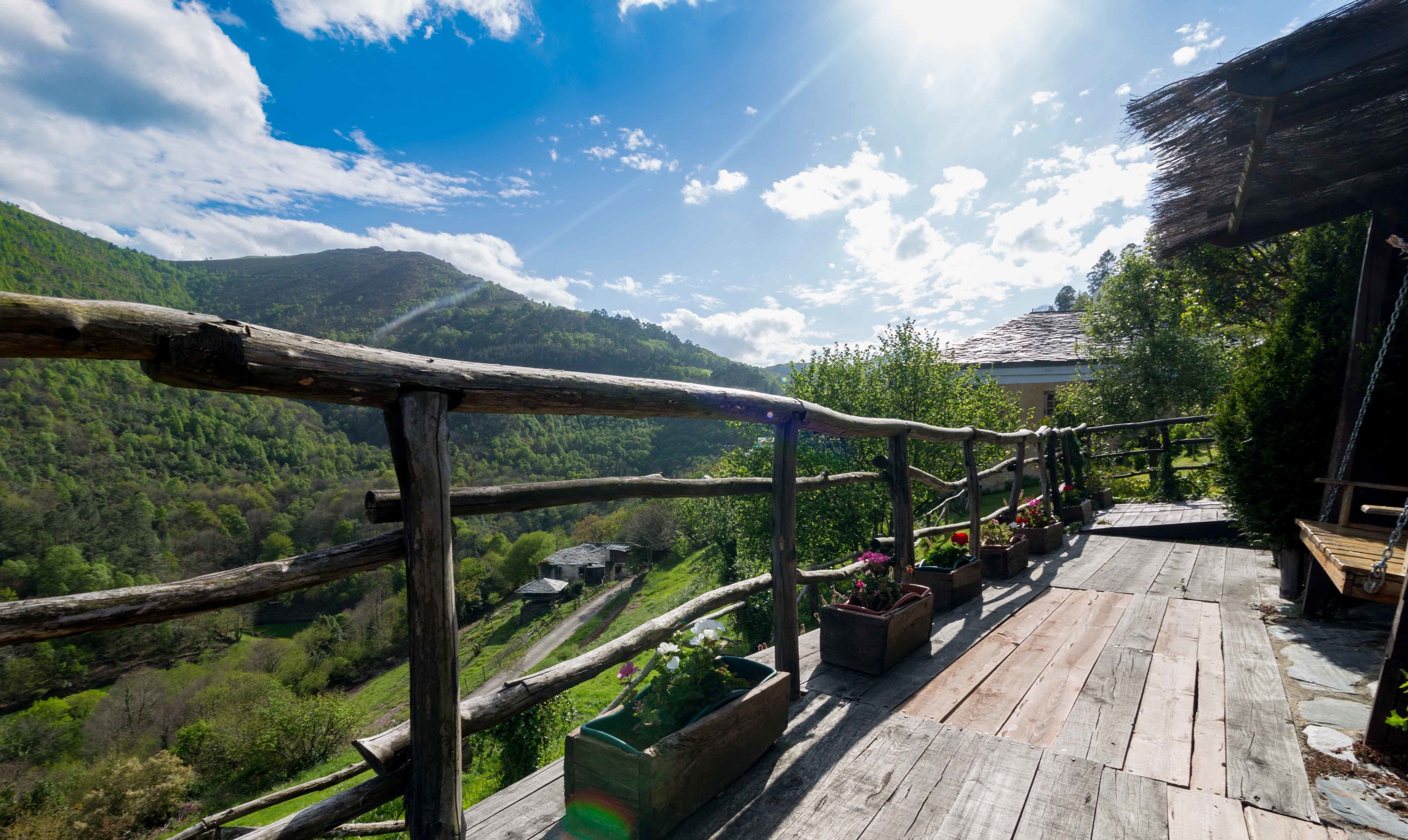A wooden deck with railings overlooking a mountainous landscape.