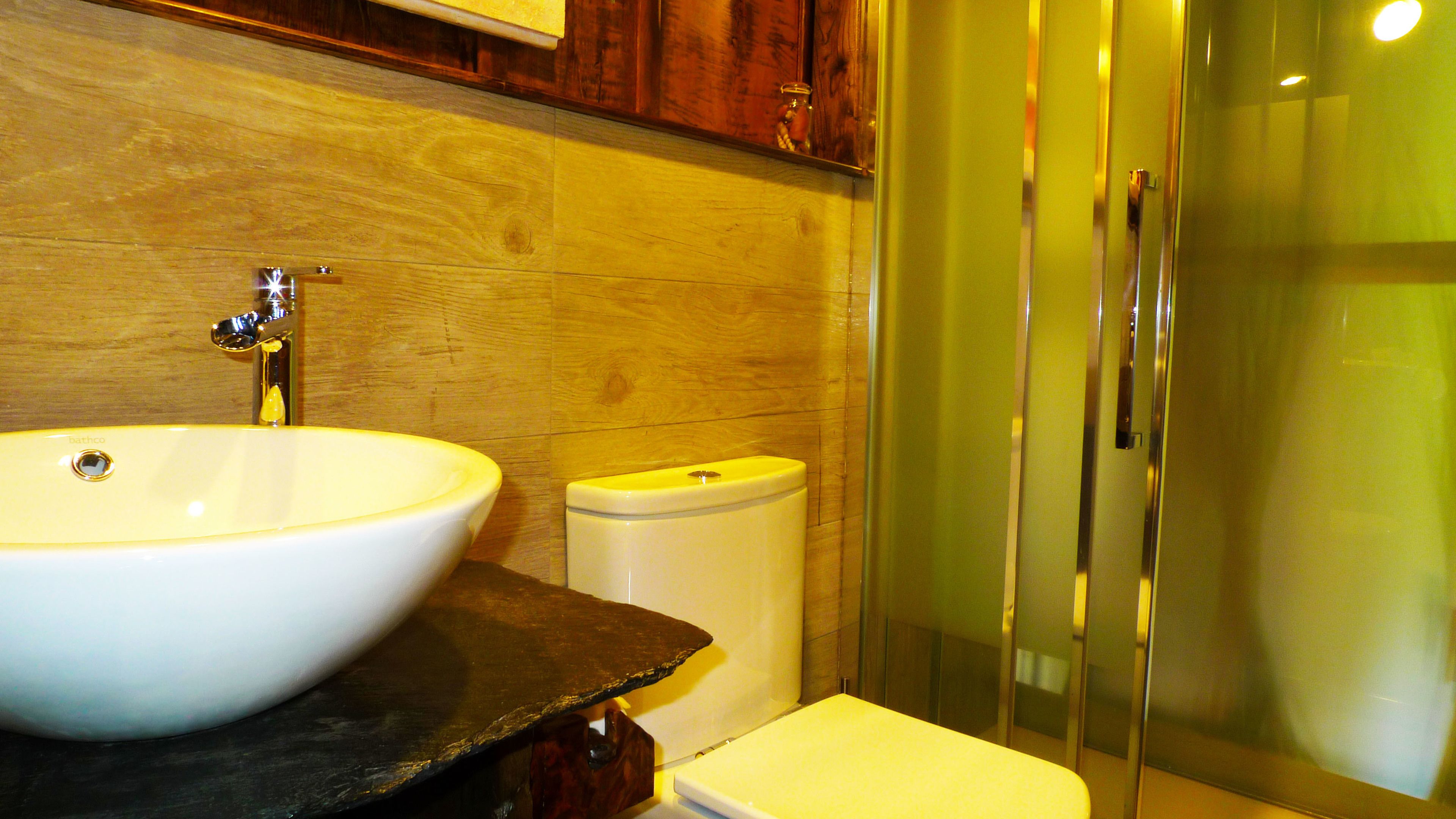 A bathroom with a white sink, a toilet, and a glass shower enclosure.