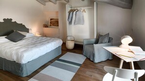 Un dormitorio con cama, escritorio con silla, lámpara colgante y perchero en la pared.