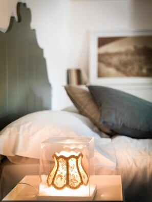A bedside table with a clear glass lamp displaying a decorative item. - Oryza B&B-Ristorante (Desana)