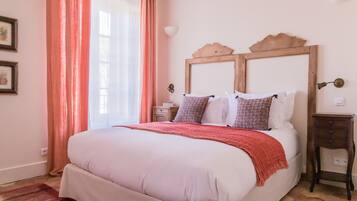 Une chambre à coucher avec un grand lit, une tête de lit en bois, une table de chevet et un plaid rouge.