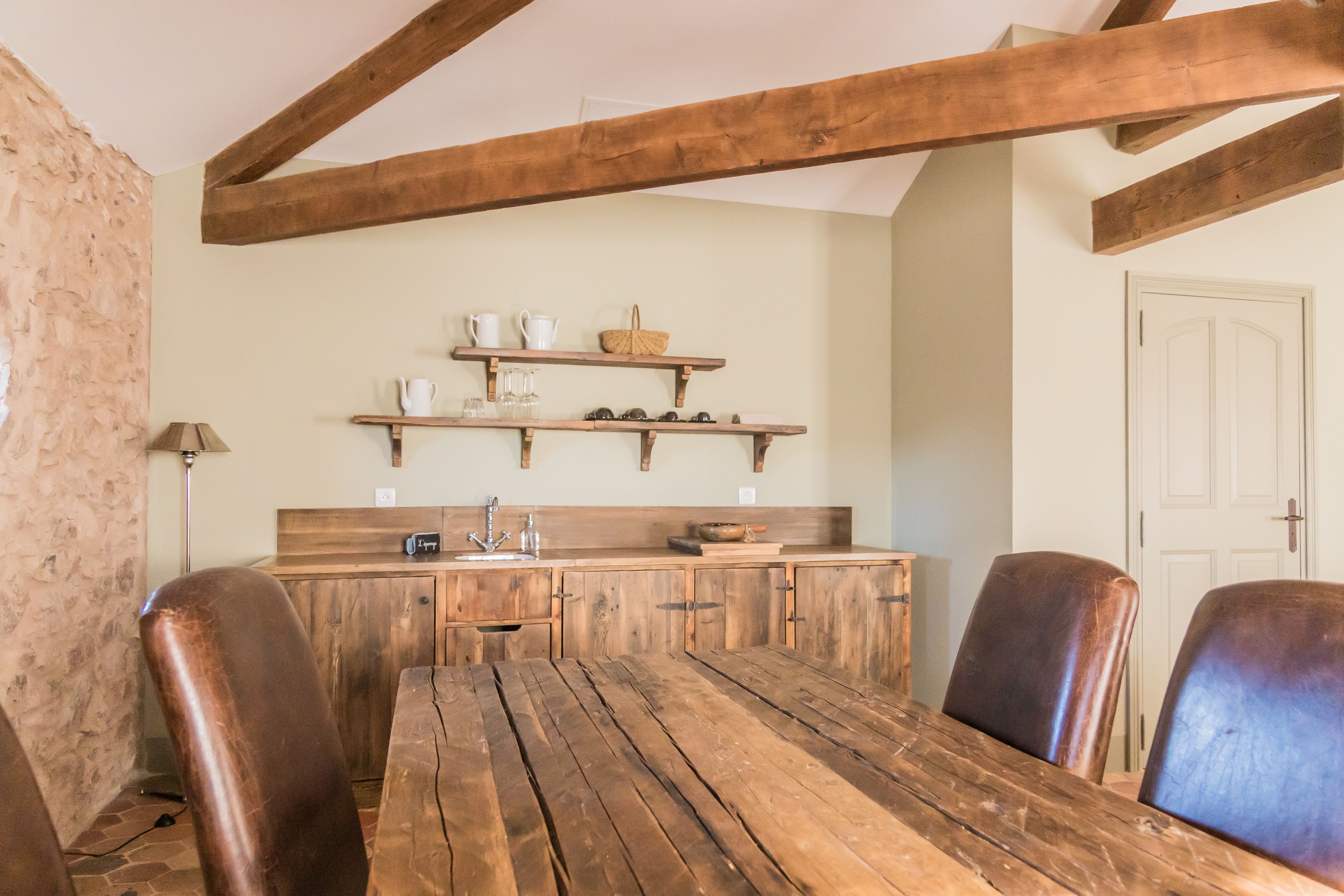 Una cocina rústica con vigas de madera, una mesa de madera y sillas de cuero.