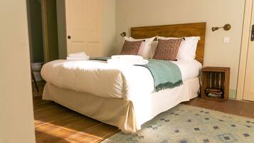 A neatly made bed with white linens, a wooden headboard, and a small bedside table with a book.