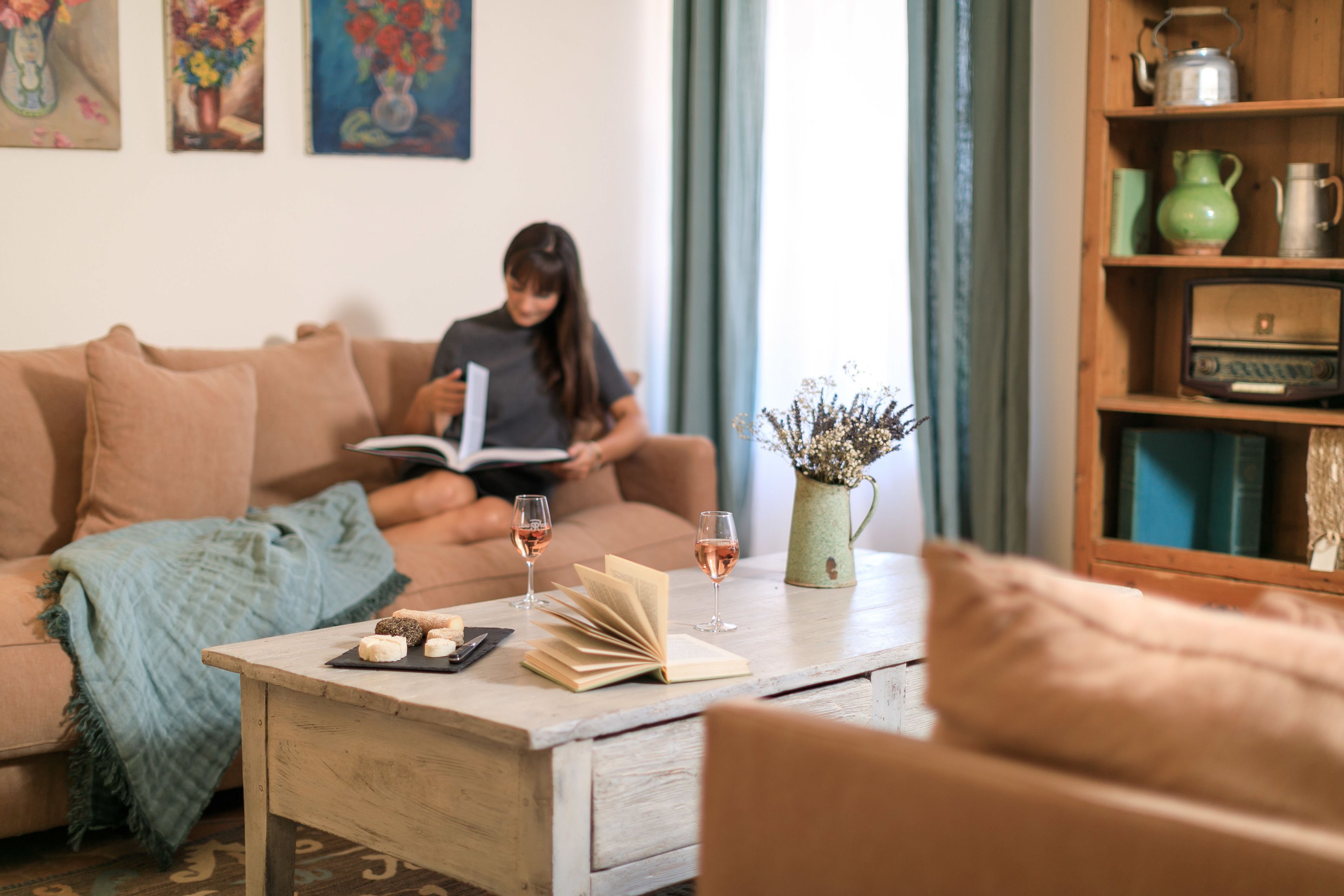 Un salon chaleureux avec un canapé, une table basse sur laquelle se trouvent un livre et des lunettes, et une bibliothèque agrémentée d'objets décoratifs.