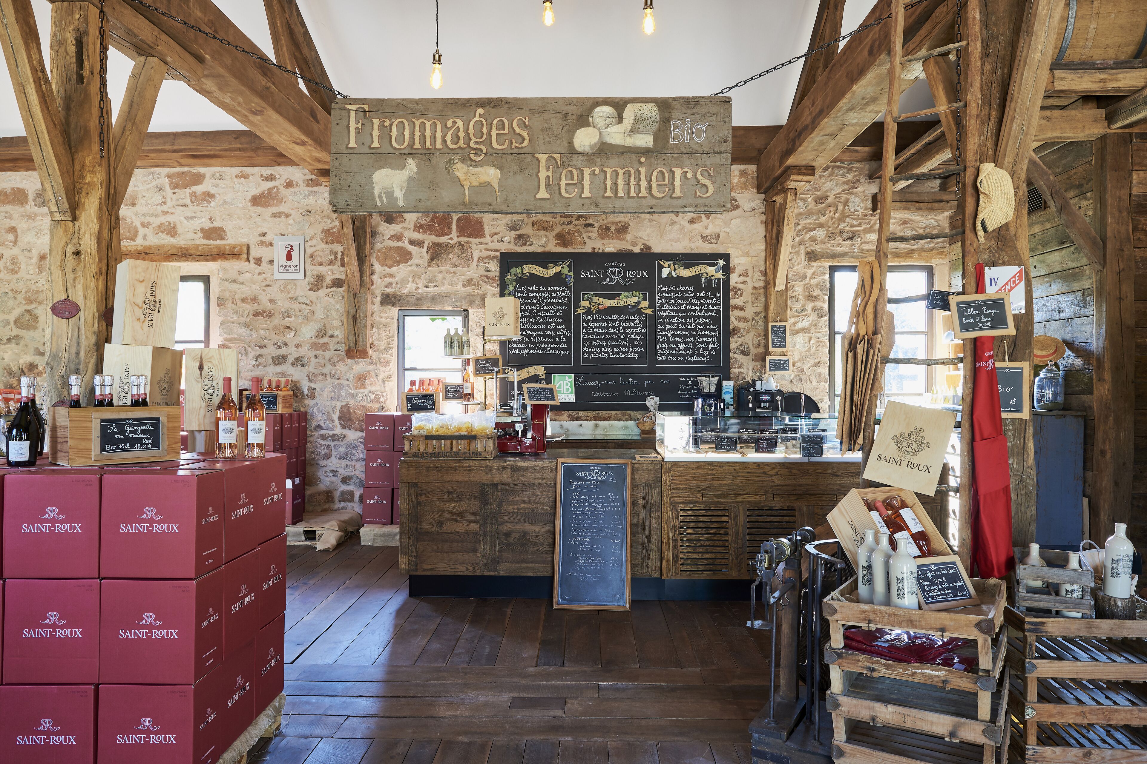 A rustic interior with wooden beams, stone walls, and a sign reading "Fromages Fermiers."