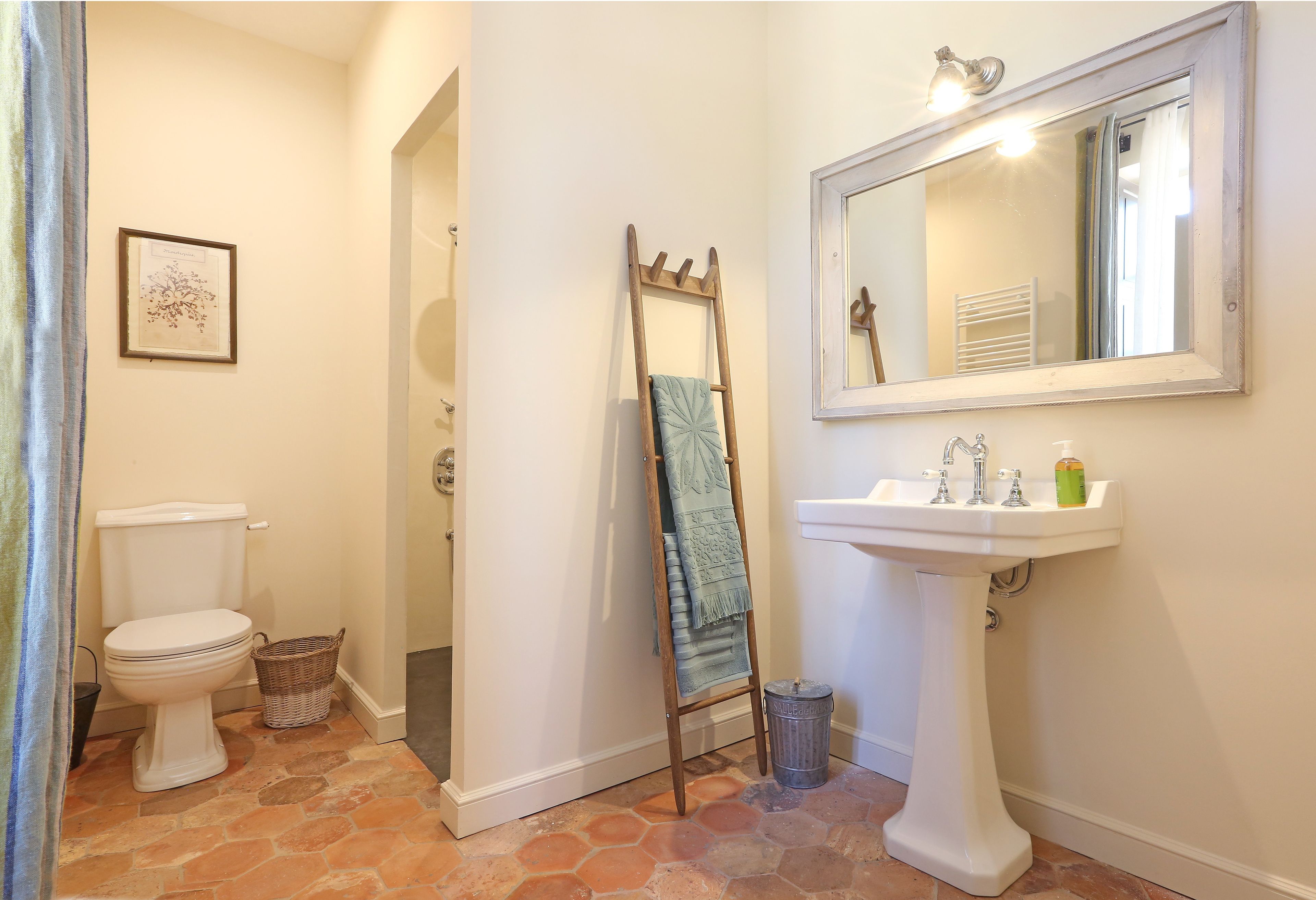 A bathroom with a toilet, sink, mirror, and a towel rack.