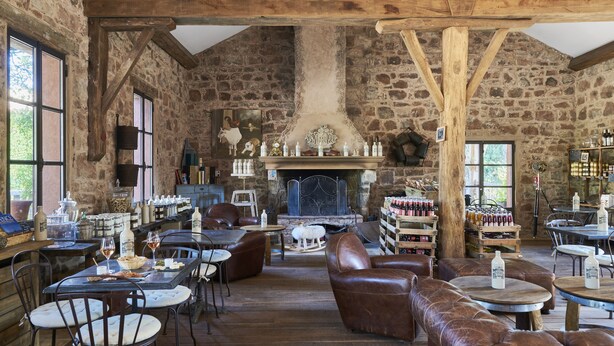 Un intérieur rustique avec des murs en pierre, des poutres en bois, des sièges en cuir et une cheminée.