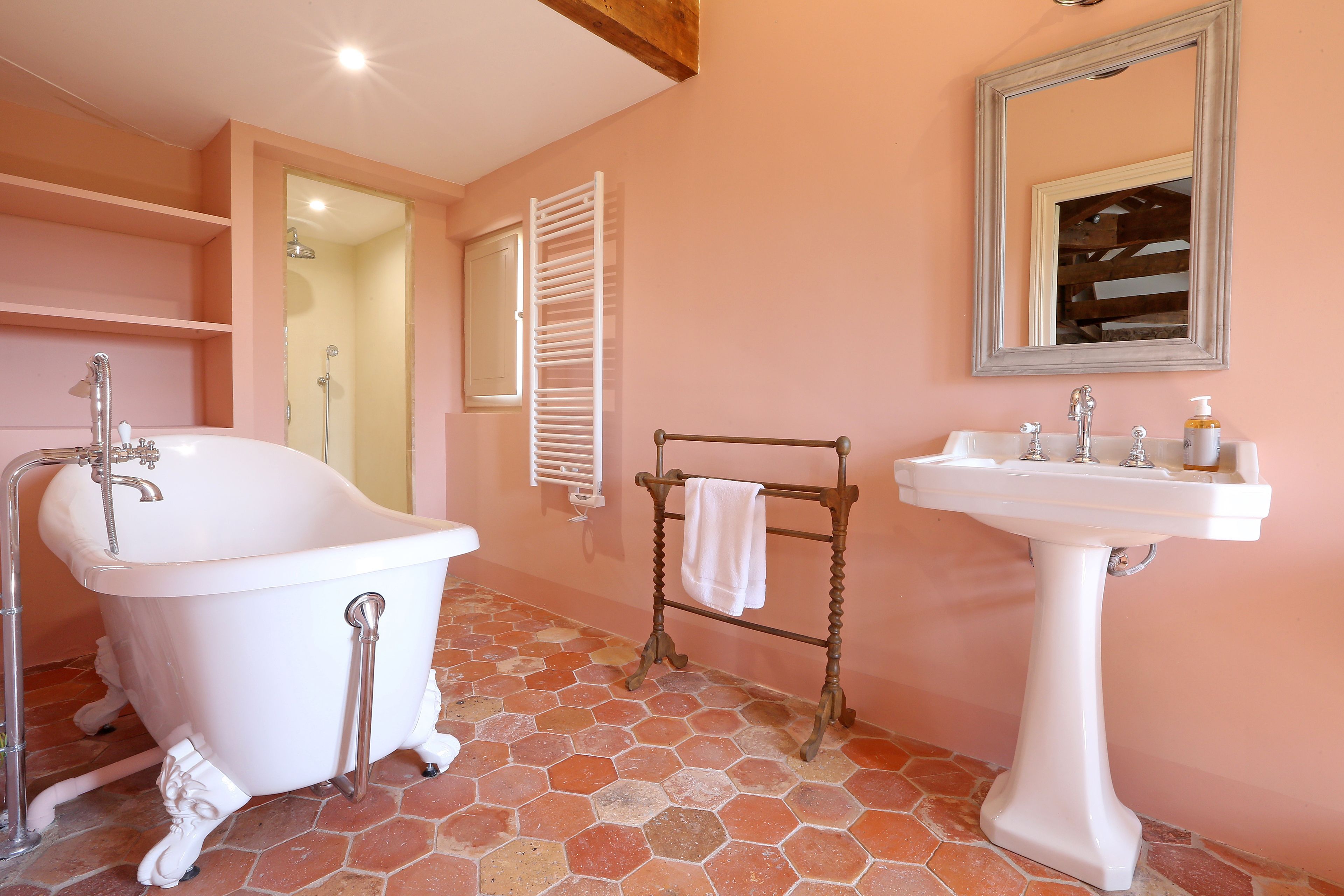 Un baño con una bañera de patas de león, un lavamanos pedestal y un espejo en la pared.