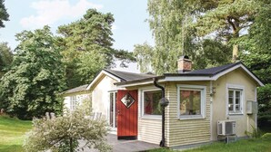 Ett litet hus i en våning med en röd dörr, en skorsten och en liten veranda.