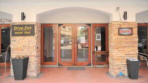 A Drop Inn entrance with stone pillars, a signboard, and a glass door. - Drop Inn Bangkok (Bangkok)