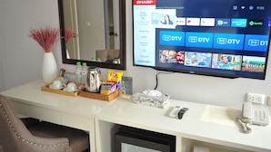 A hotel room with a desk, a flat-screen TV displaying streaming services, a mirror, and a telephone. - Drop Inn Bangkok (Bangkok)