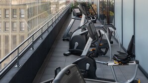 A gym with treadmills and exercise equipment on a balcony with a city view. - Appart’hôtel Odalys City - Nantes Cité des congrès (Nantes)