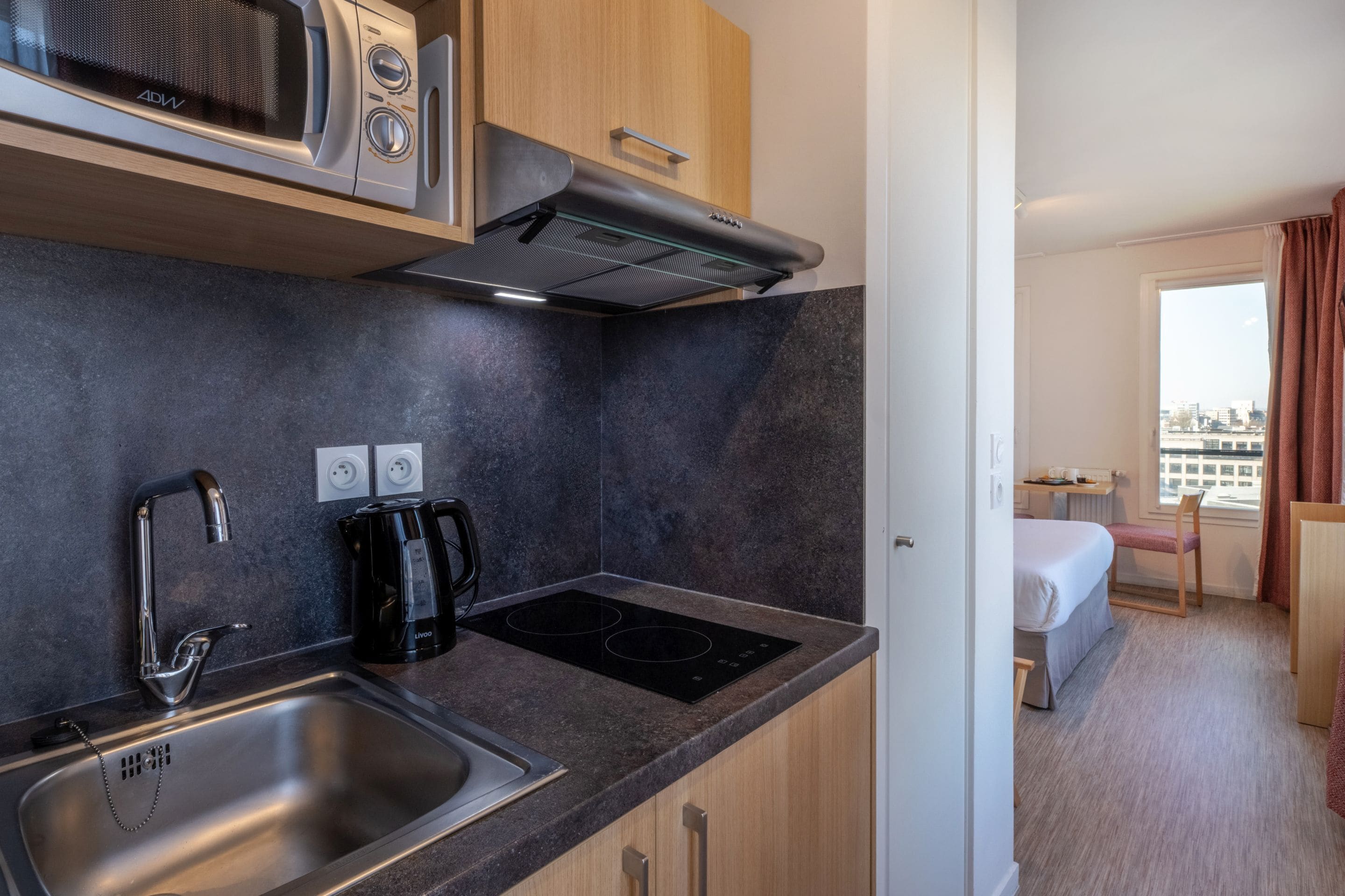 A compact kitchenette with a built-in microwave, a stovetop, and a sink.